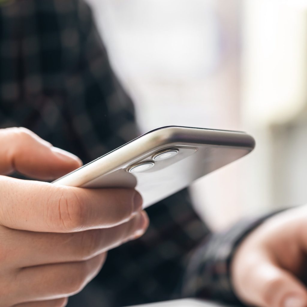 A man holds a smartphone and works at a laptop, the concept of working in the office, technology at work.